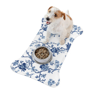 Dog feeding mat - dog sitting on a blue floral-patterned mat with a bowl of food on a white background